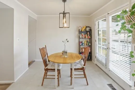 Dining area with ornamental molding and light floors