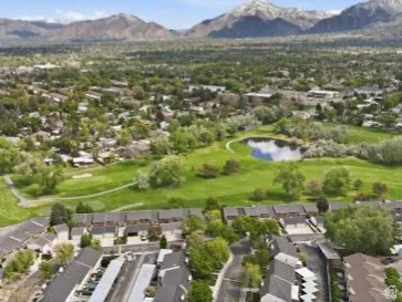 Aerial view of residential area featuring a golf club and a water and mountain view