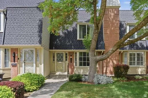 View of front facade with a chimney, a shingled roof, and brick siding