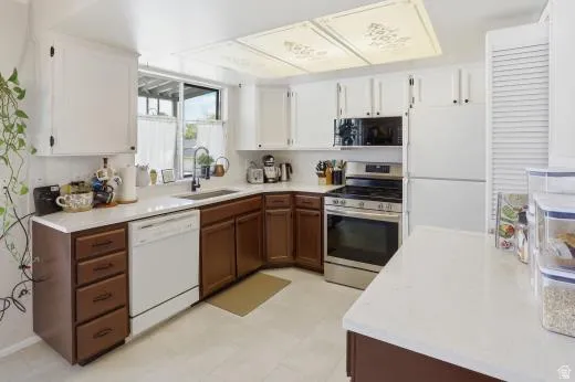 Two tone kitchen featuring two tone cabinetry, white appliances, and light flooring