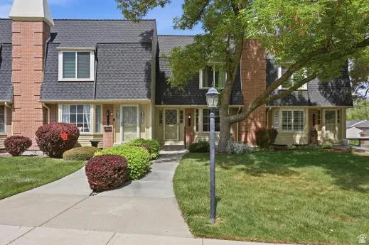 View of front of house with a front lawn, brick siding, a chimney, and a shingled roof