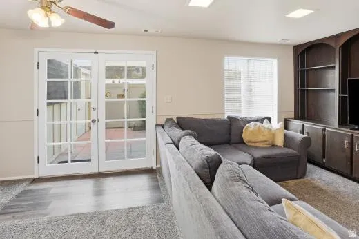 Living area with a ceiling fan, wood finished floors, and french doors