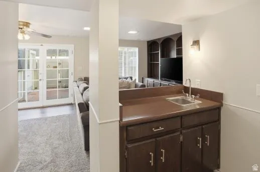 Kitchen with dark wood finish cabinetry, dark countertops, a ceiling fan, and light carpet