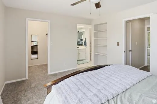 Carpeted bedroom with connected bathroom and a ceiling fan