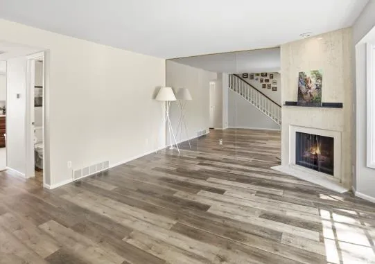 Unfurnished living room with a large fireplace and dark wood-type flooring