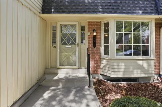 View of exterior entry with a shingled roof and brick siding