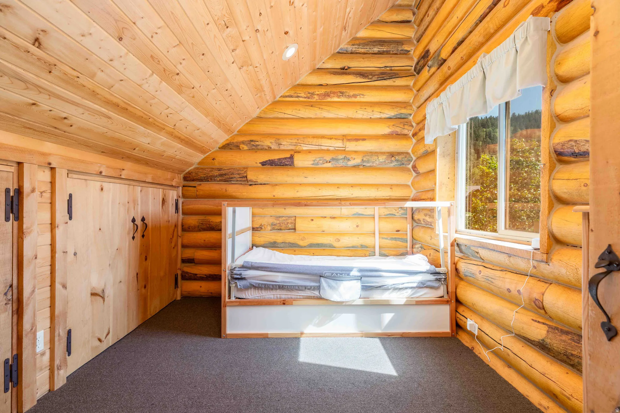 Unfurnished bedroom with carpet floors, a vaulted wood ceiling, and log walls