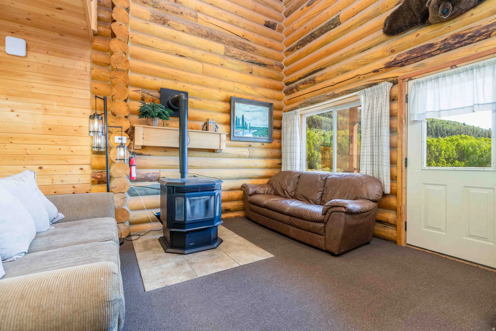 Carpeted living area featuring log walls, a wood stove, and a high ceiling
