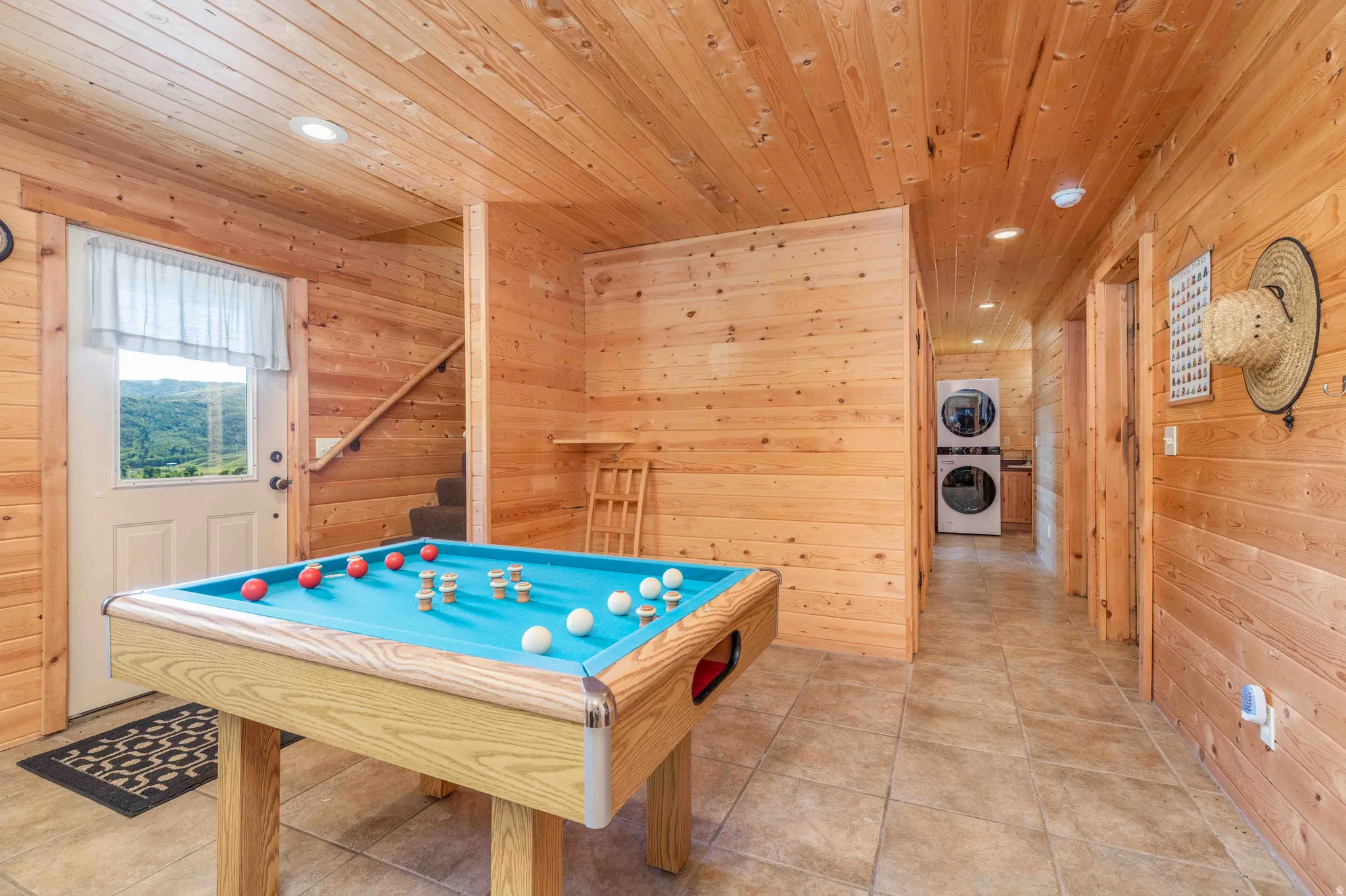 Playroom featuring wooden walls, pool table, stacked washer and clothes dryer, tile patterned flooring, and recessed lighting
