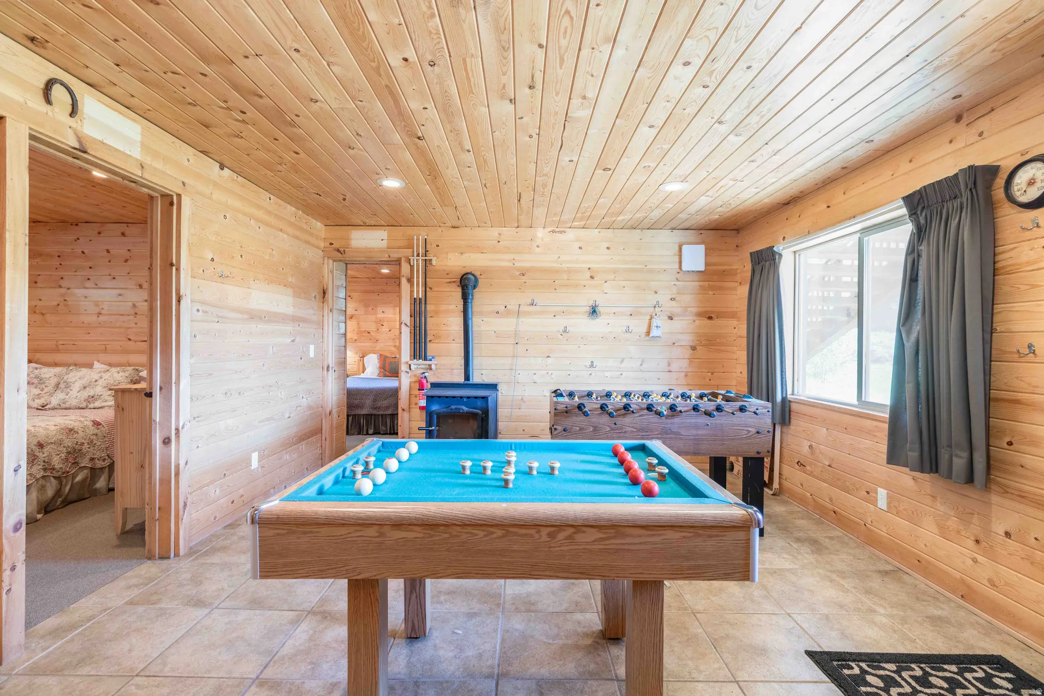 Recreation room with wooden walls, a wood stove, wooden ceiling, light tile patterned floors, and recessed lighting