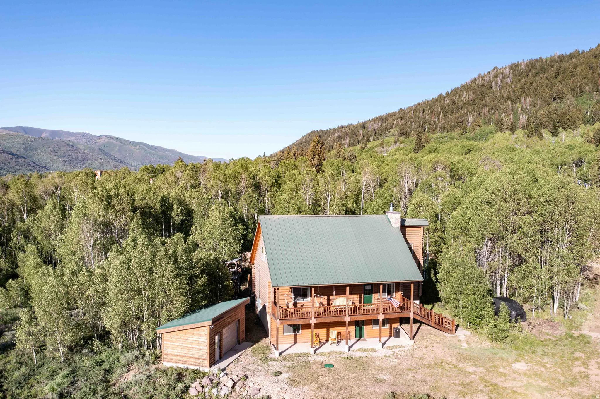 Aerial view of property and surrounding area with a forest and a mountain backdrop