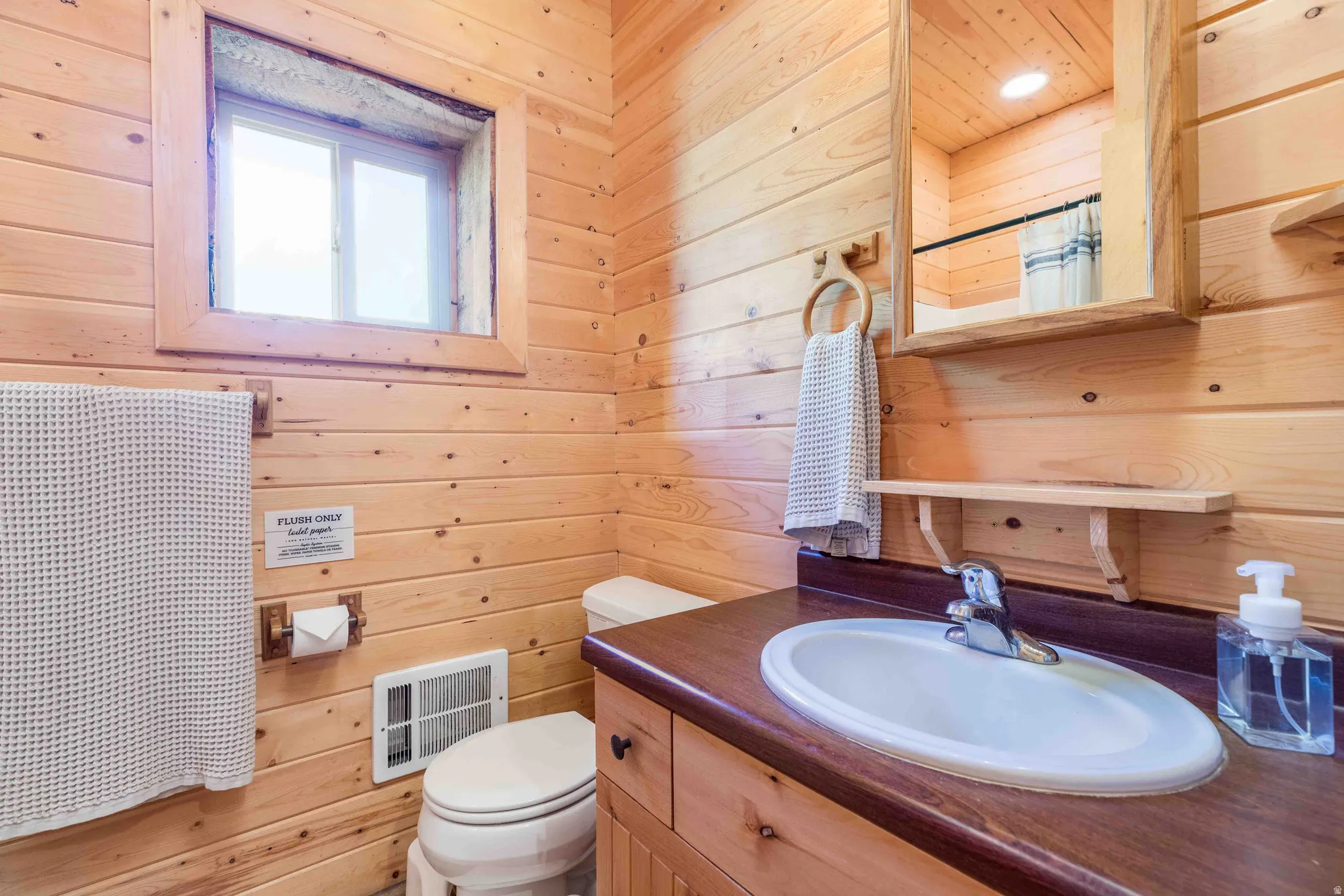 Bathroom with wooden walls, vanity, and a shower with curtain