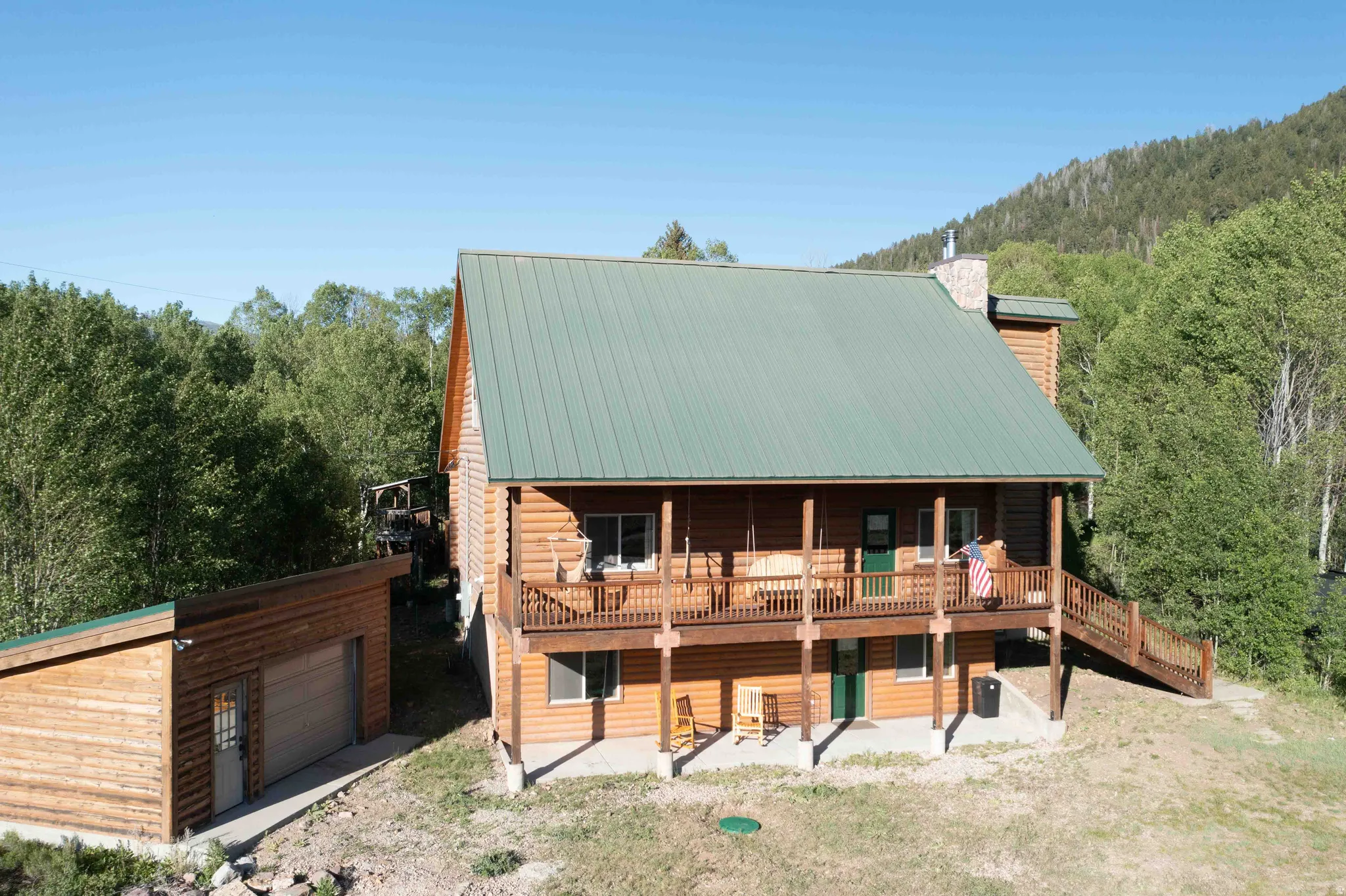 Log cabin featuring an outbuilding, a chimney, a wooden deck, and a metal roof