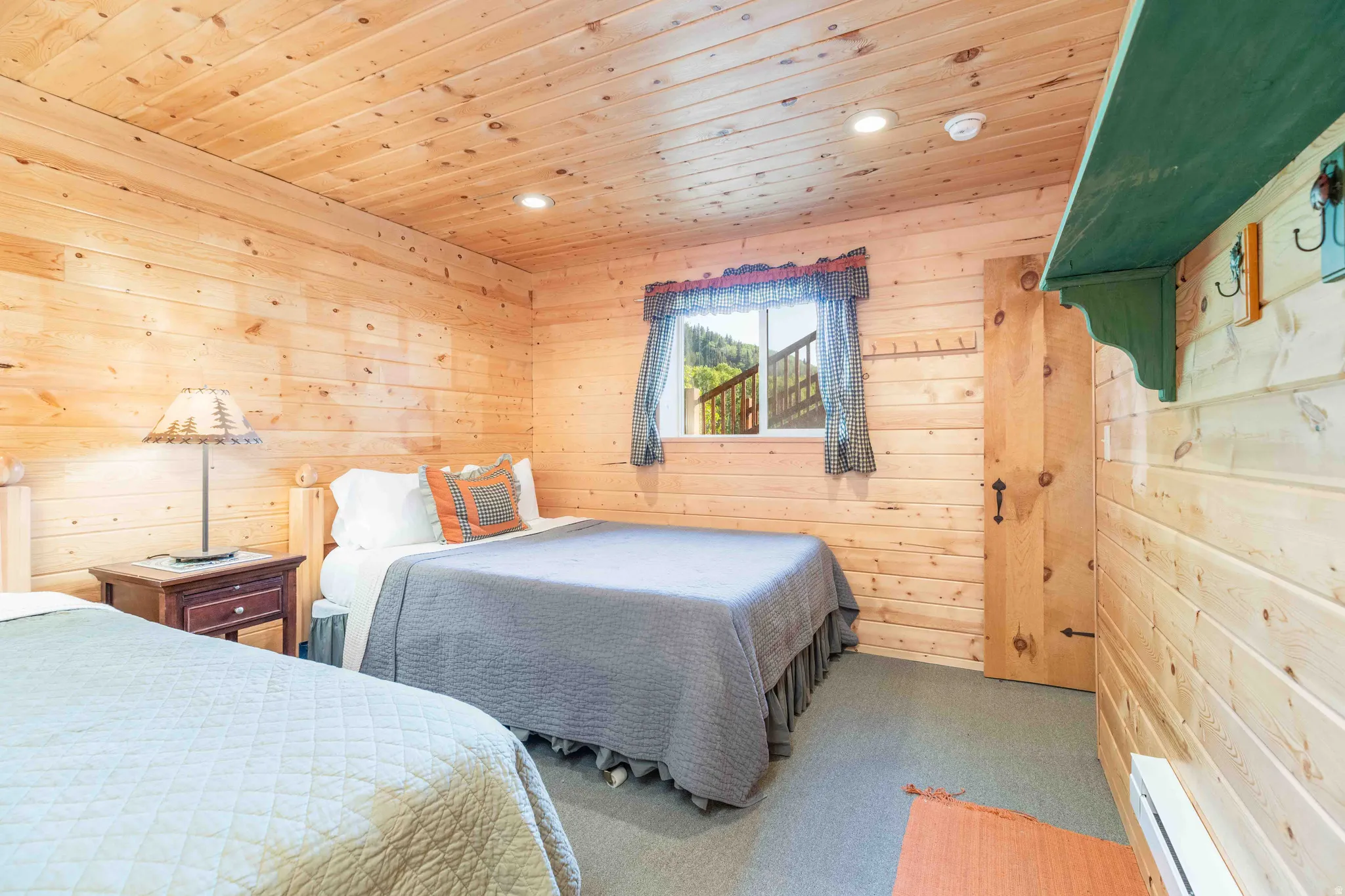 Carpeted bedroom featuring wooden walls, wooden ceiling, baseboard heating, and recessed lighting