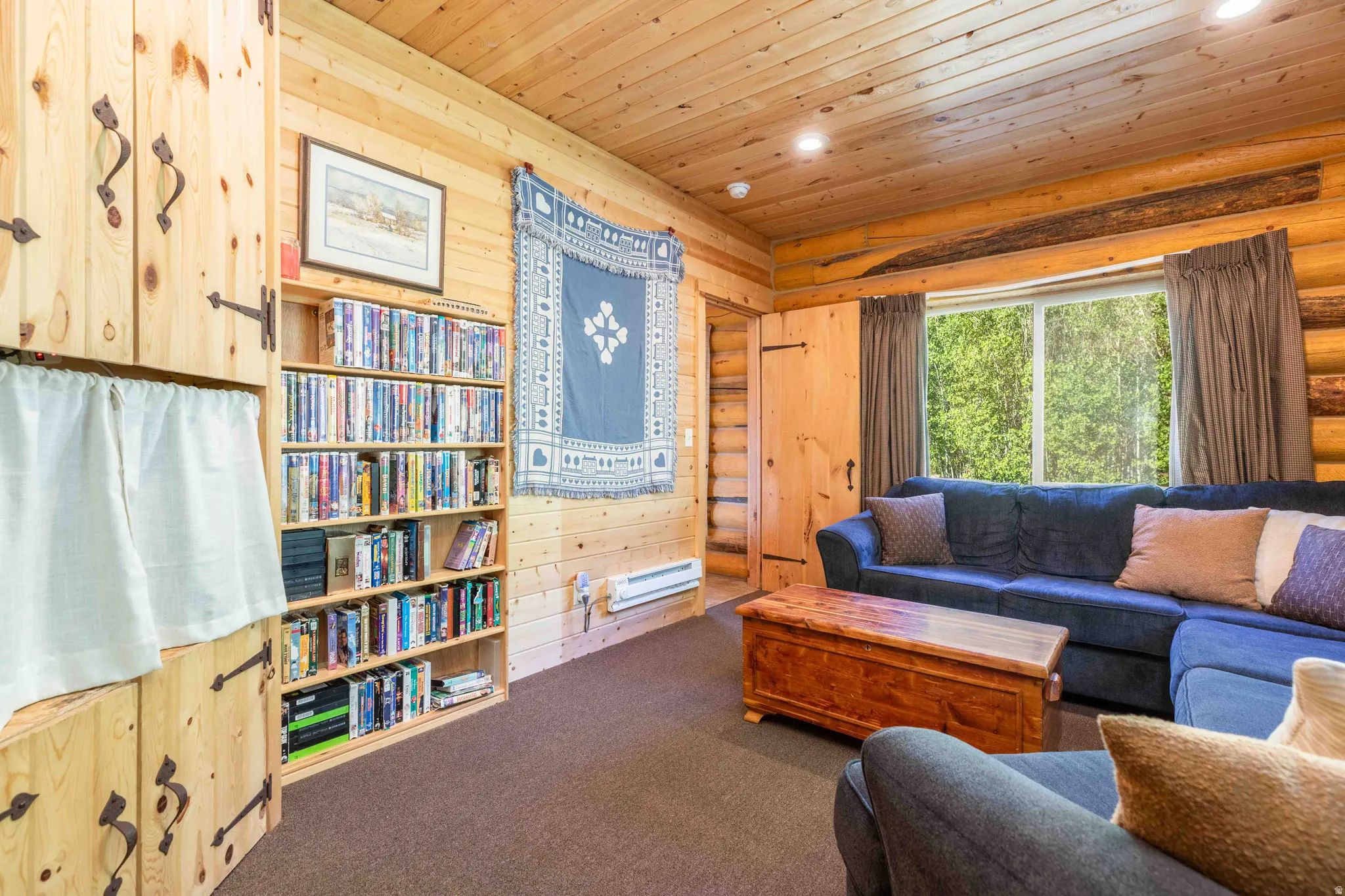 Carpeted living room featuring wood ceiling, rustic walls, recessed lighting, a baseboard radiator, and wooden walls