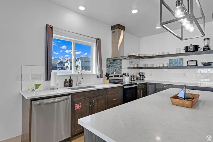 Kitchen with dishwasher, electric range oven, light stone countertops, exhaust hood, and dark wood finish cabinets