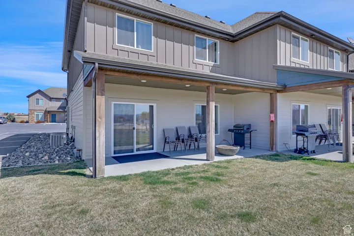 Rear view of house featuring board and batten siding, a yard, and a patio area