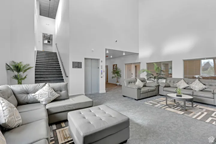 Carpeted living area with elevator and a high ceiling