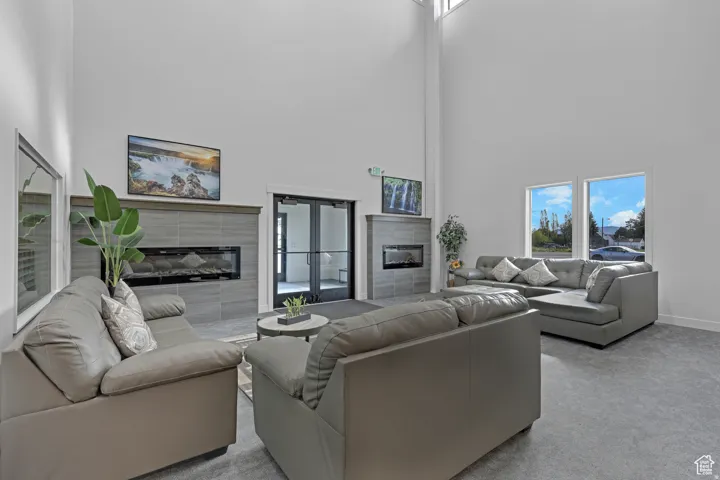Carpeted living room featuring a tiled fireplace and a high ceiling