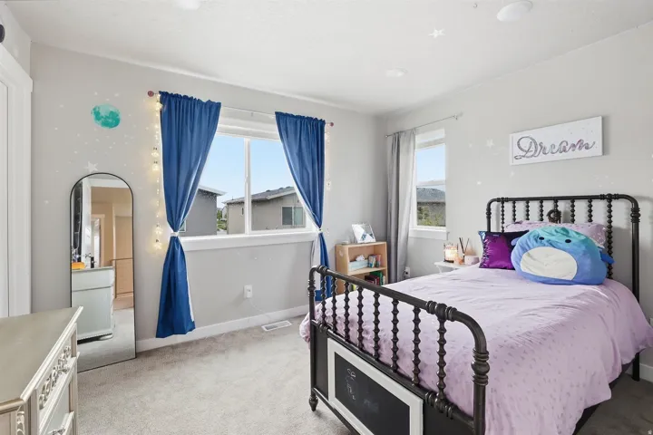 Bedroom featuring light colored carpet and multiple windows
