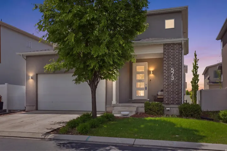 View of front of home featuring driveway, a garage, stucco siding, and brick siding