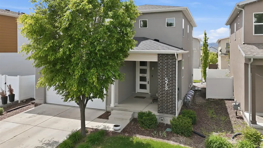 Contemporary home featuring a garage, a shingled roof, driveway, and stucco siding