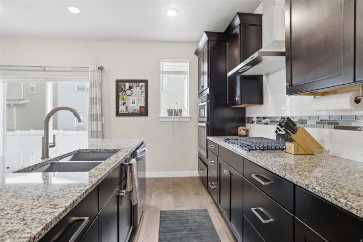 Kitchen featuring light stone countertops, light wood-type flooring, healthy amount of natural light, tasteful backsplash, and recessed lighting