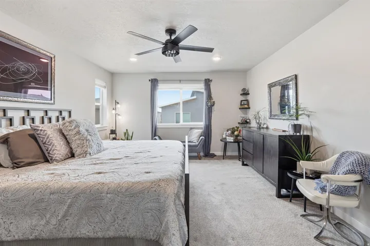 Bedroom featuring light colored carpet, a ceiling fan, and a textured ceiling