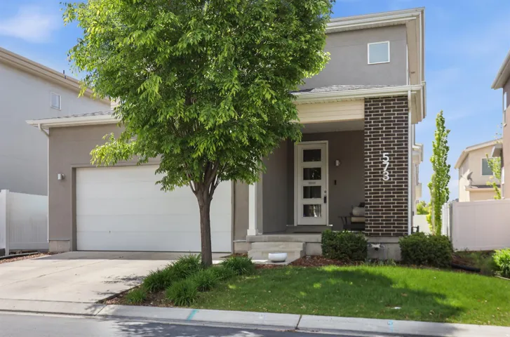 View of front of house featuring a porch, driveway, brick siding, stucco siding, and an attached garage
