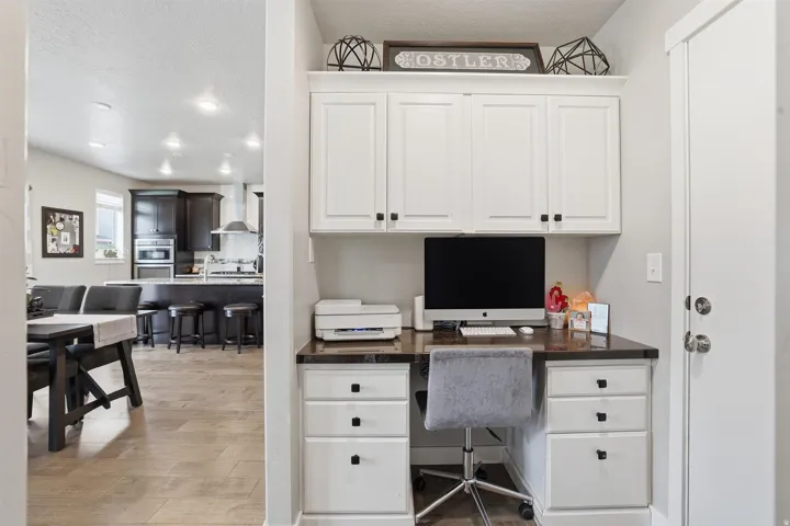 Office featuring a textured ceiling, built in desk, and light wood finished floors