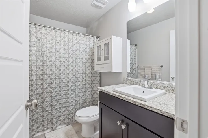 Bathroom featuring vanity, a shower with shower curtain, a textured ceiling, and light tile patterned floors
