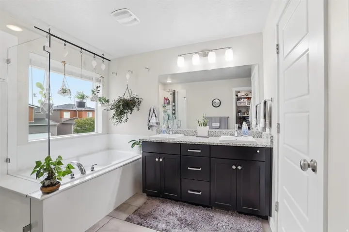 Bathroom with double vanity, a bath, a stall shower, light tile patterned floors, and a textured ceiling