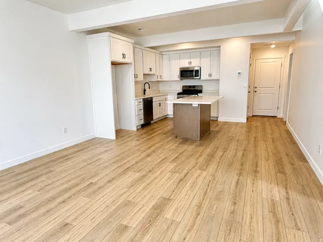 Kitchen with stainless steel appliances, light wood-style floors, a center island, dual tone cabinetry, and open floor plan
