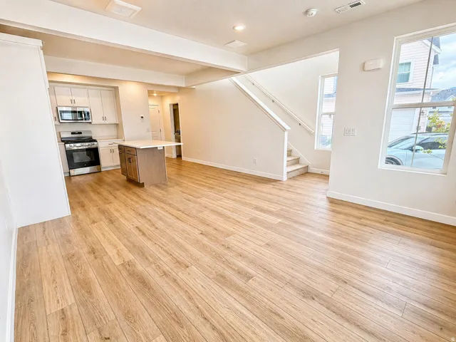 Two tone kitchen with open floor plan, light countertops, stainless steel appliances, a center island, and light wood-type flooring