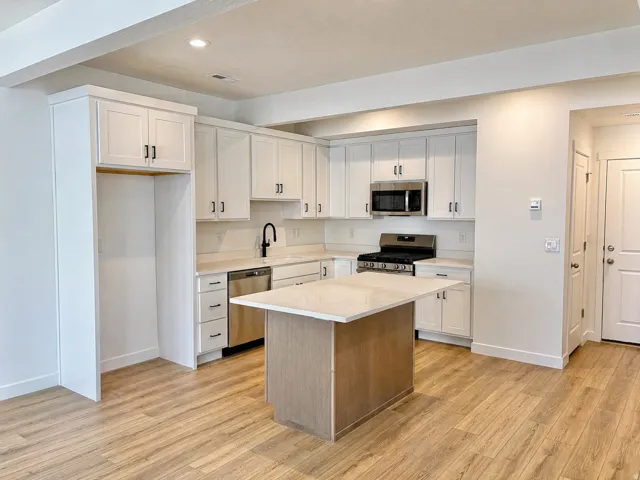Kitchen with stainless steel appliances, light wood-style floors, a kitchen island, recessed lighting, and dual tone cabinetry