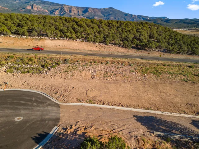 Cleared and graded lot featuring a paved road, concrete curbing, and a mountainous backdrop