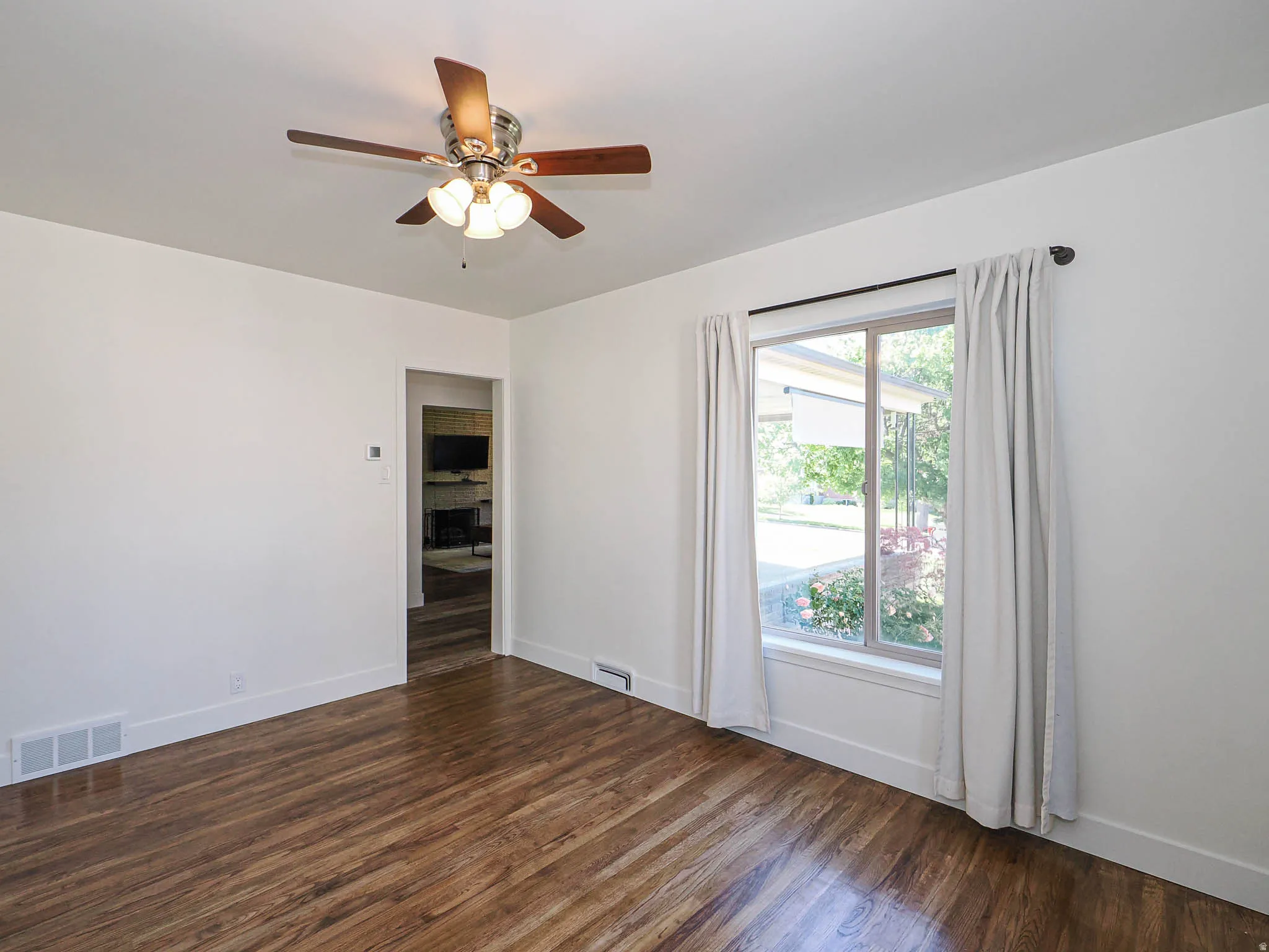 Spare room featuring dark wood-style floors and ceiling fan