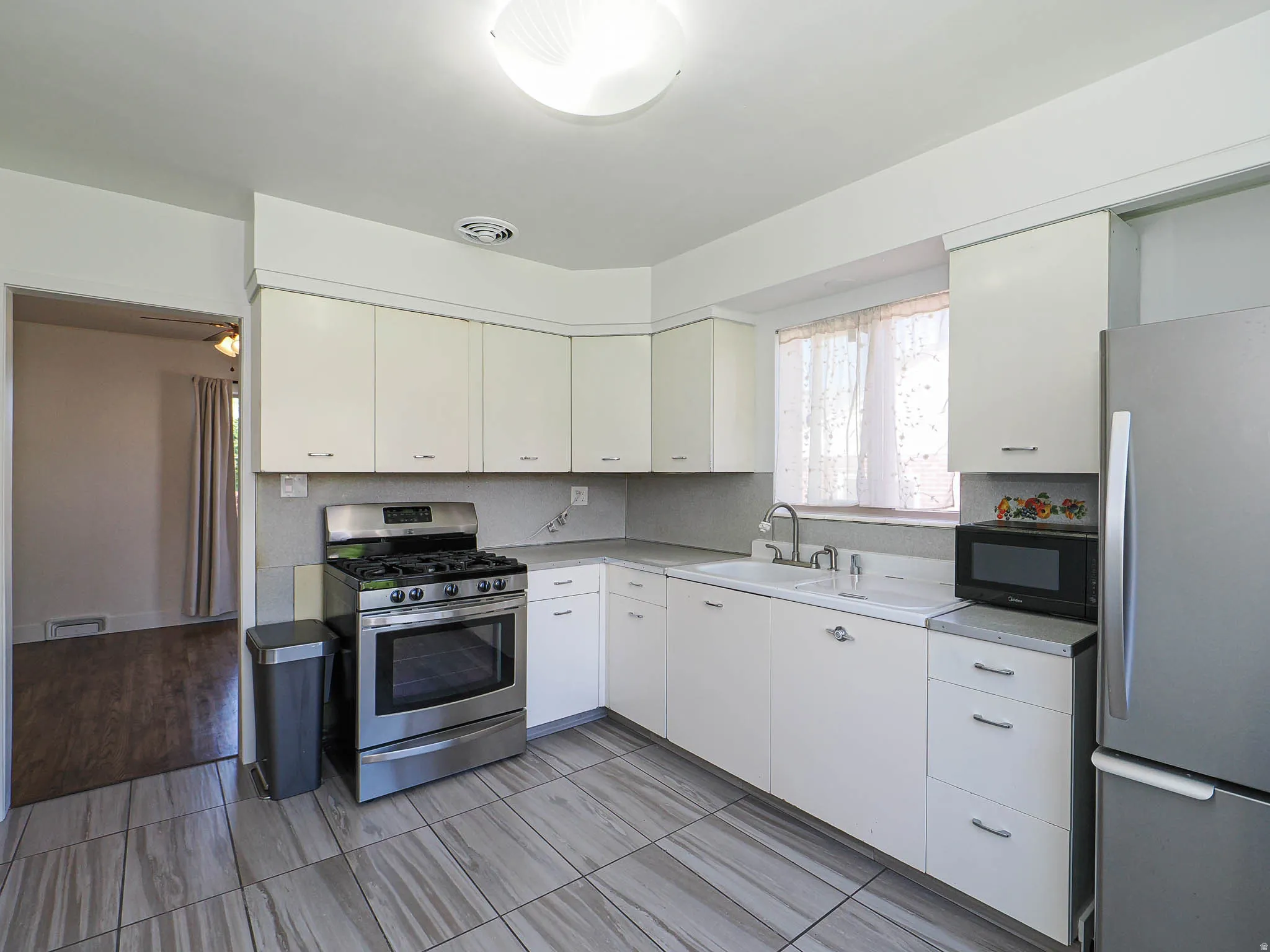 Kitchen with stainless steel appliances, light countertops, and white cabinetry