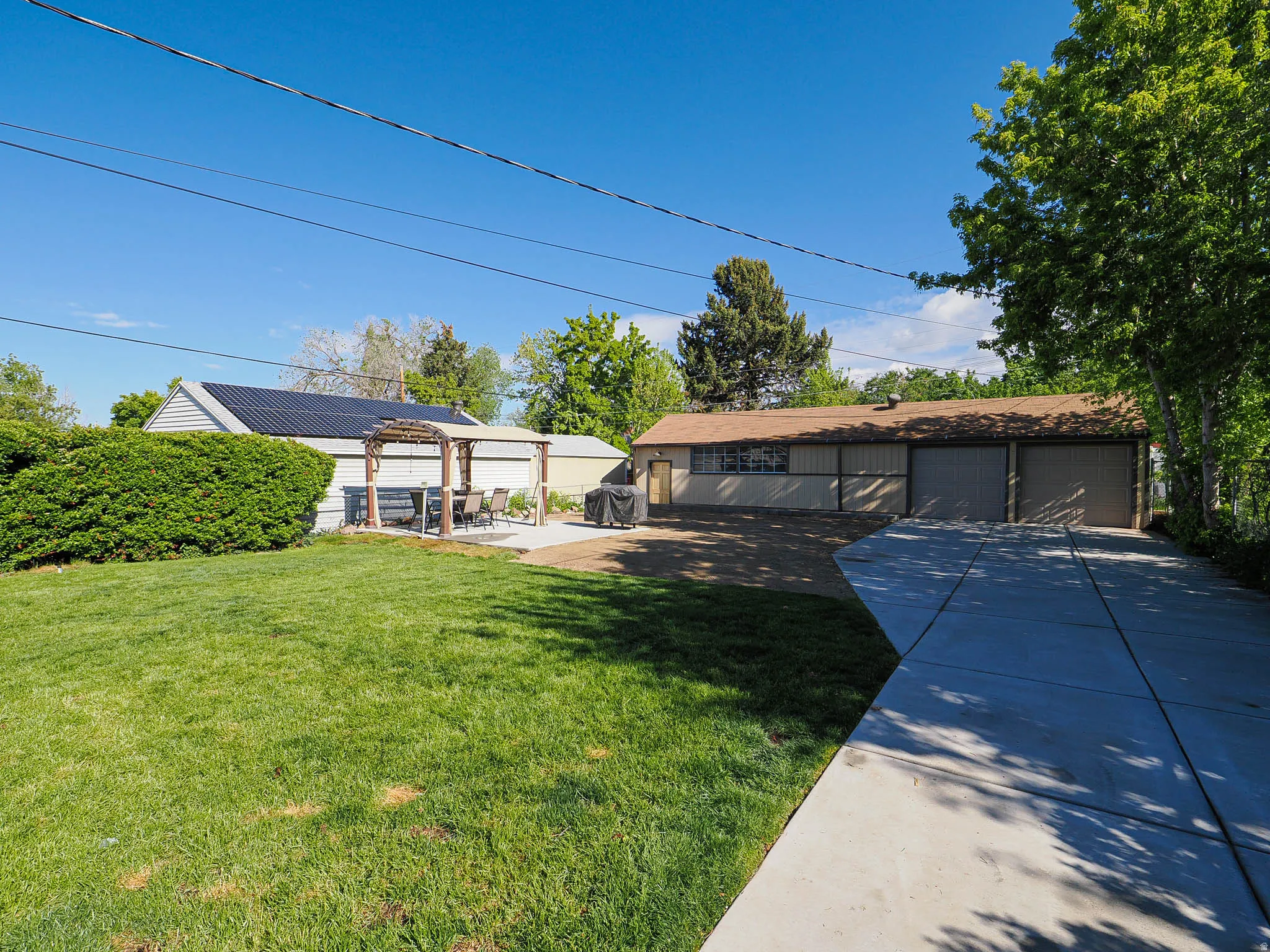 View of yard featuring an outdoor structure, a detached garage, a patio, and a pergola