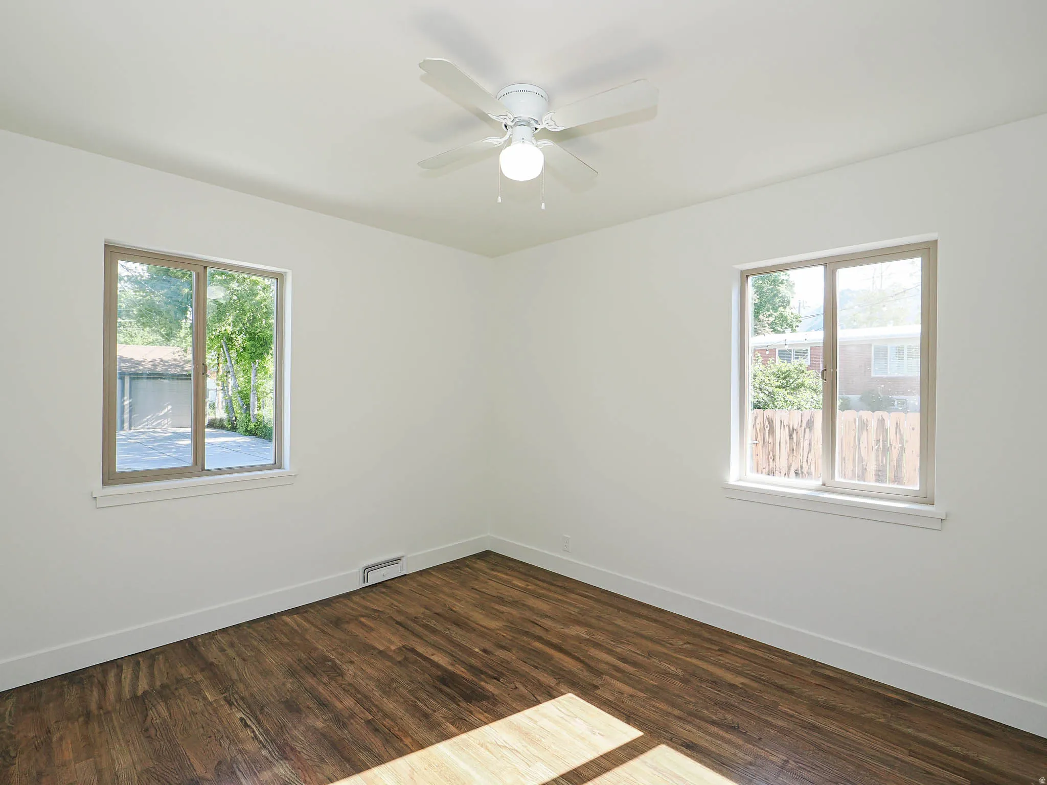 Empty room featuring dark wood-style floors and ceiling fan
