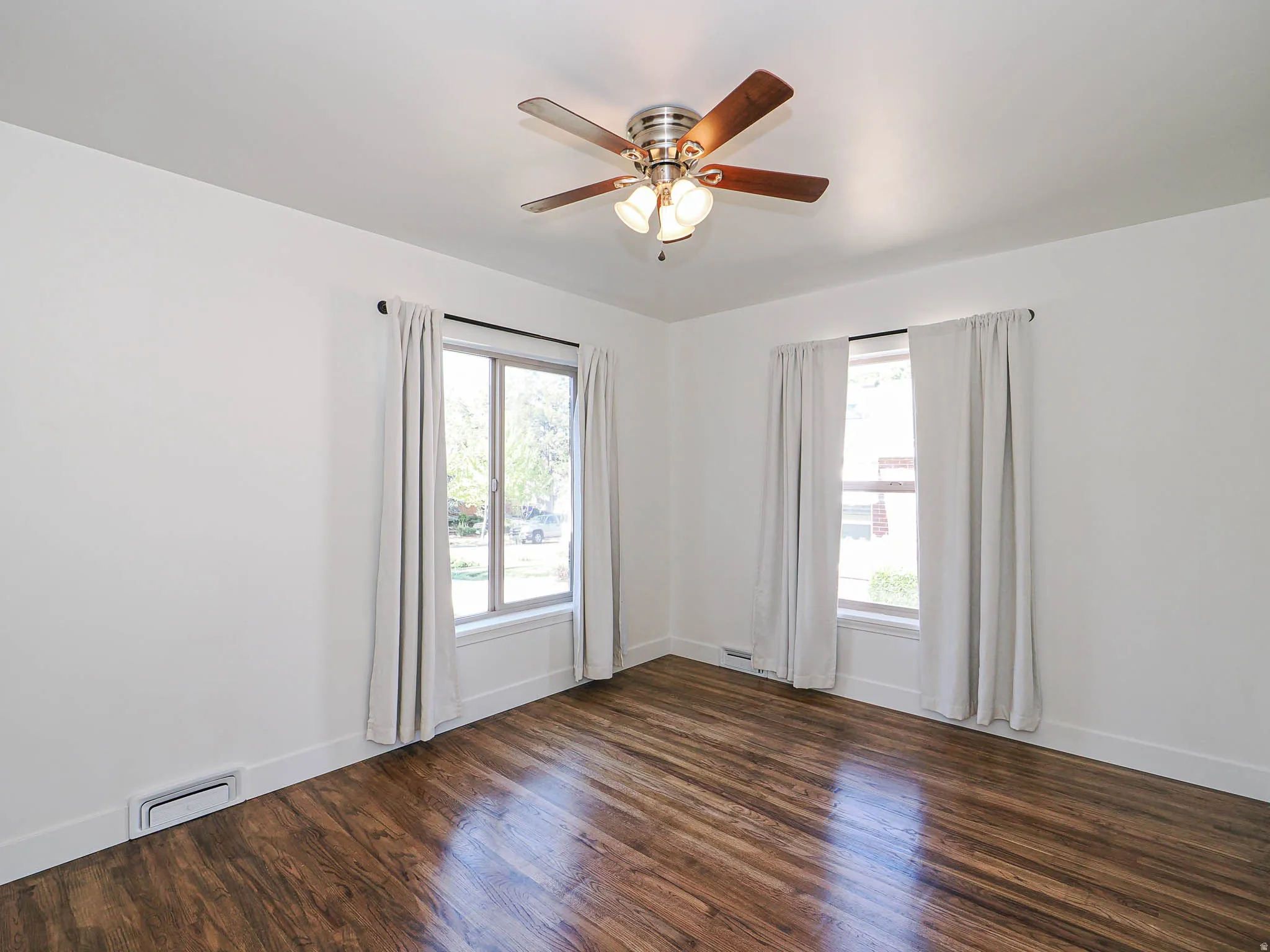 Unfurnished room featuring dark wood-style floors, ceiling fan, and healthy amount of natural light