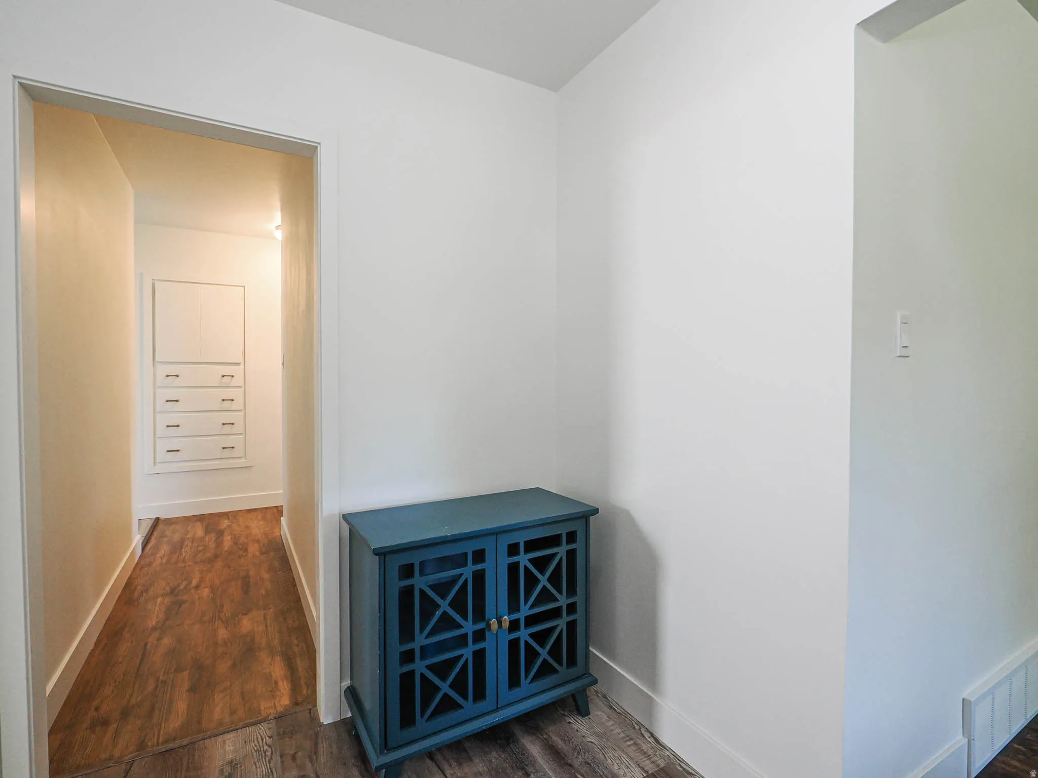 Hallway with dark wood-type flooring and baseboards