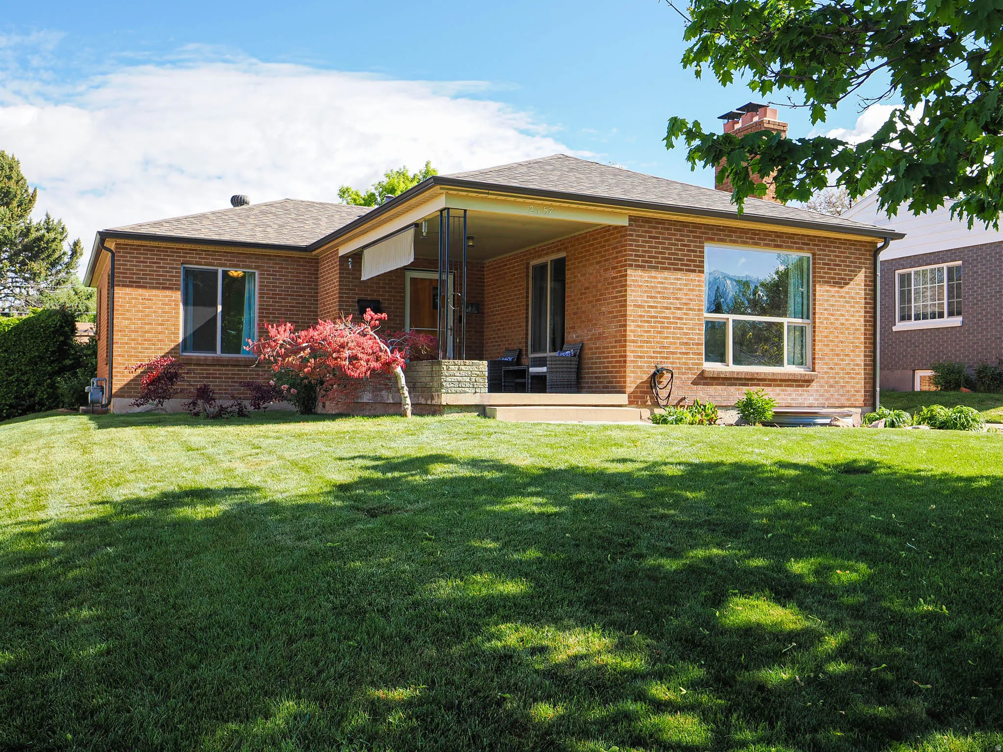 Rear view of house featuring brick siding, a yard, and roof with shingles