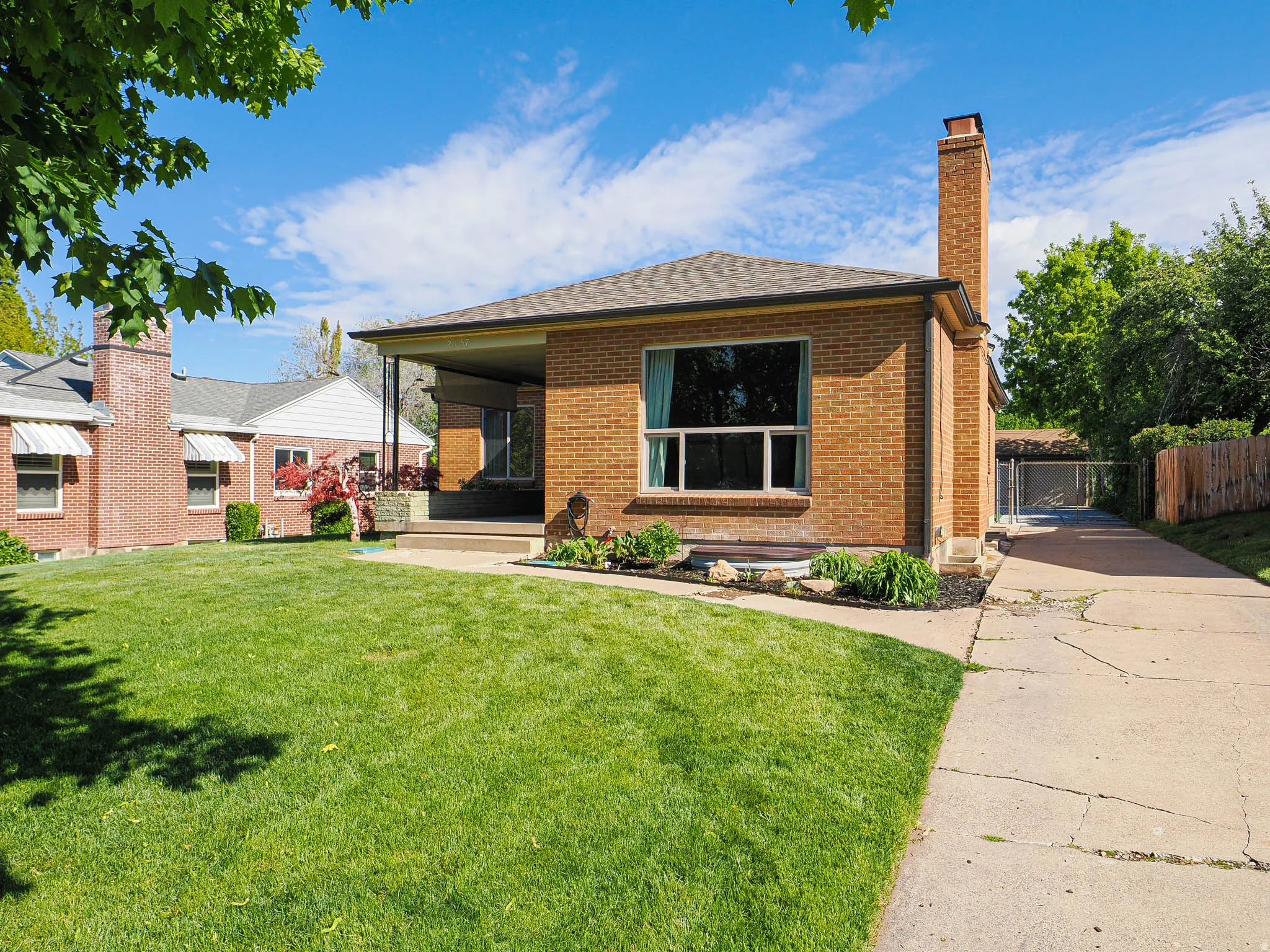 View of front of home with brick siding, a chimney, a porch, and a shingled roof