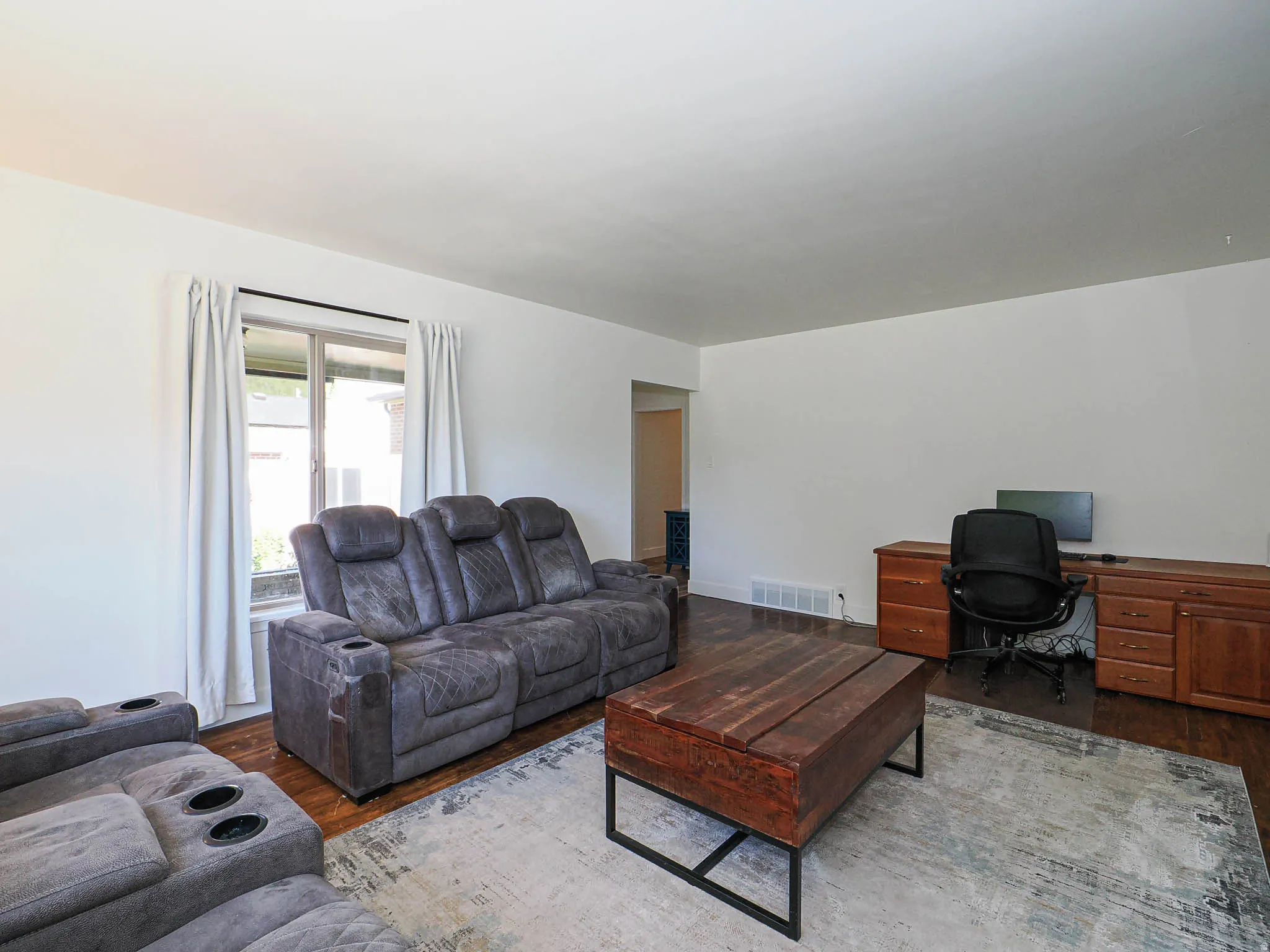 Living area with a desk and dark wood-style floors