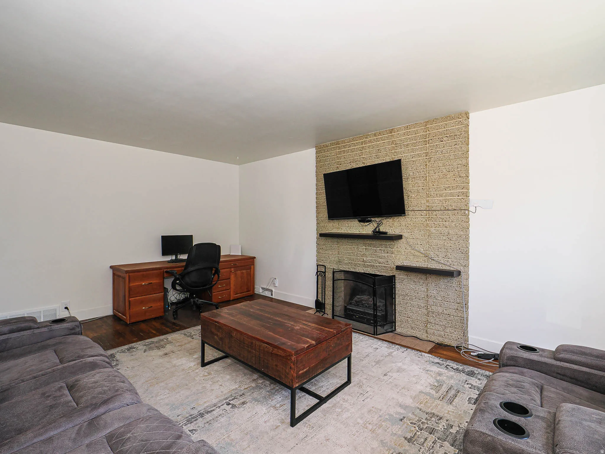 Living area with a fireplace, wood finished floors, and an office area