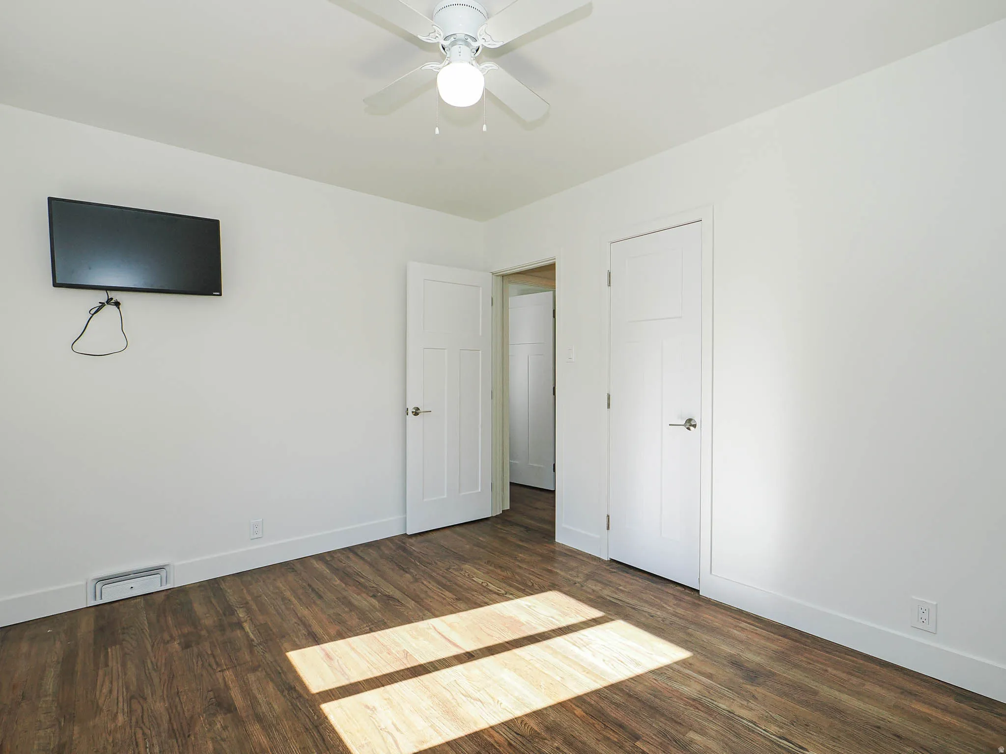Unfurnished bedroom with dark wood-type flooring and ceiling fan