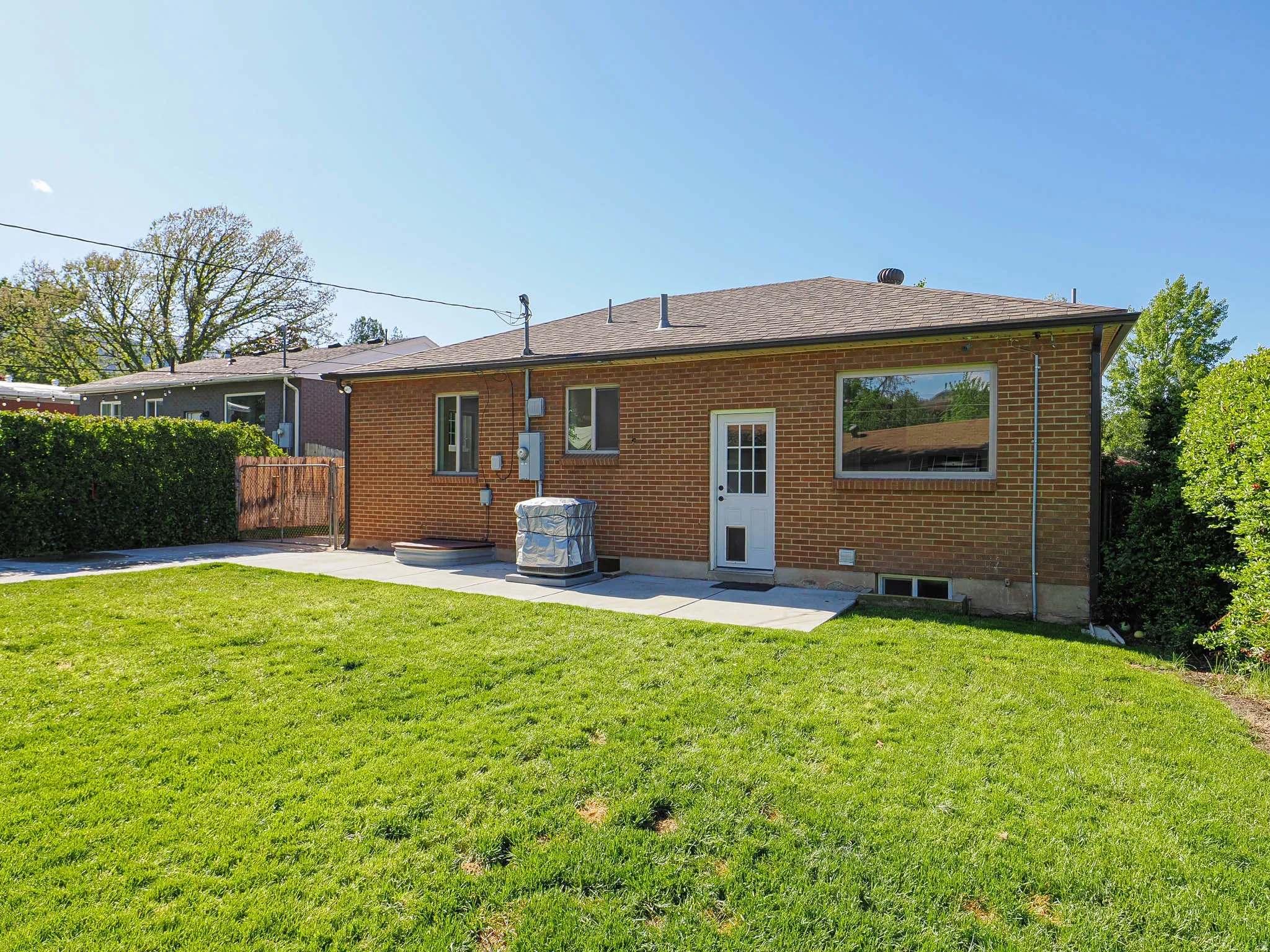 Rear view of property with brick siding, a patio area, and a shingled roof