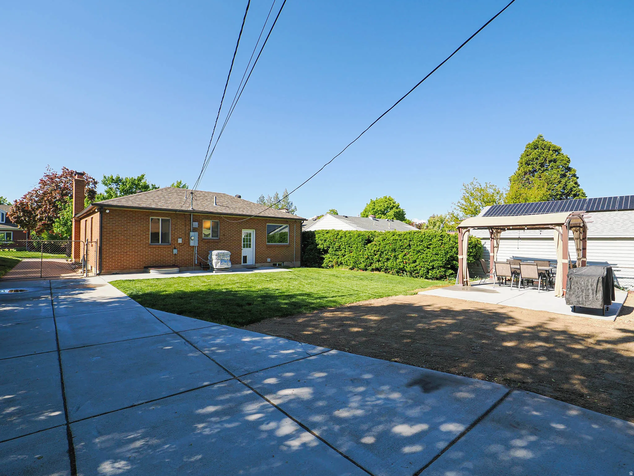Rear view of house featuring a patio area, brick siding, a fenced backyard, and a chimney