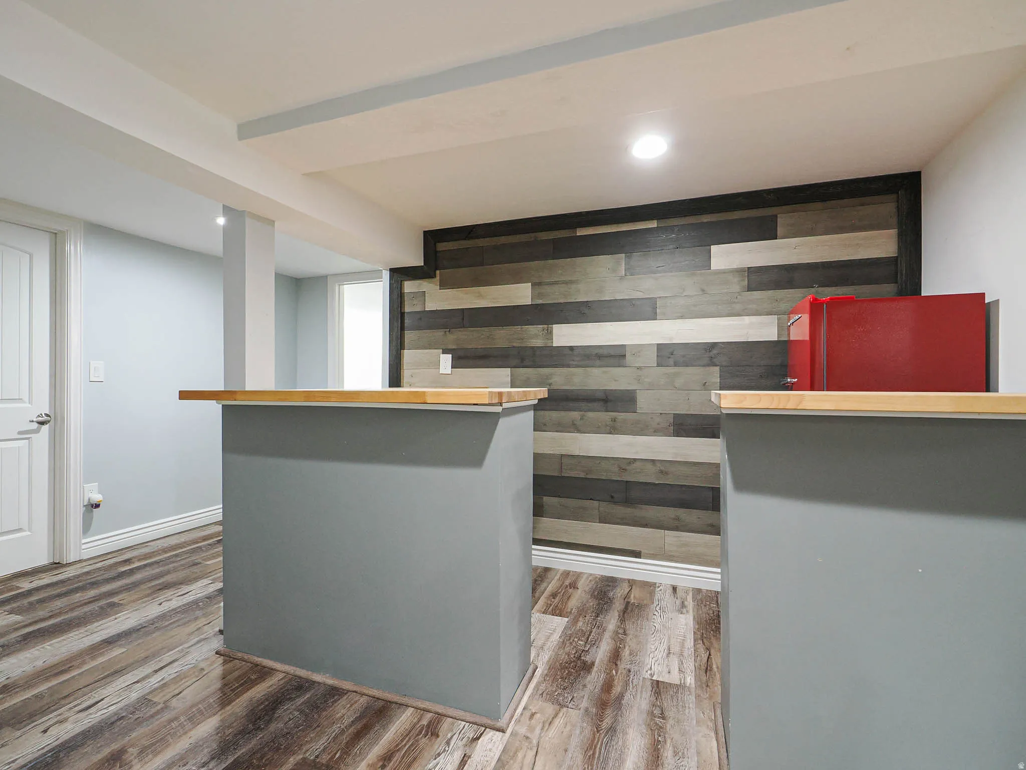 Indoor dry bar with wood walls, wood finished floors, recessed lighting, an accent wall, and gray cabinetry